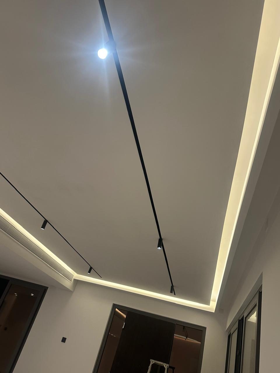 Recessed ceiling cove with warm concealed LED and black track spotlights