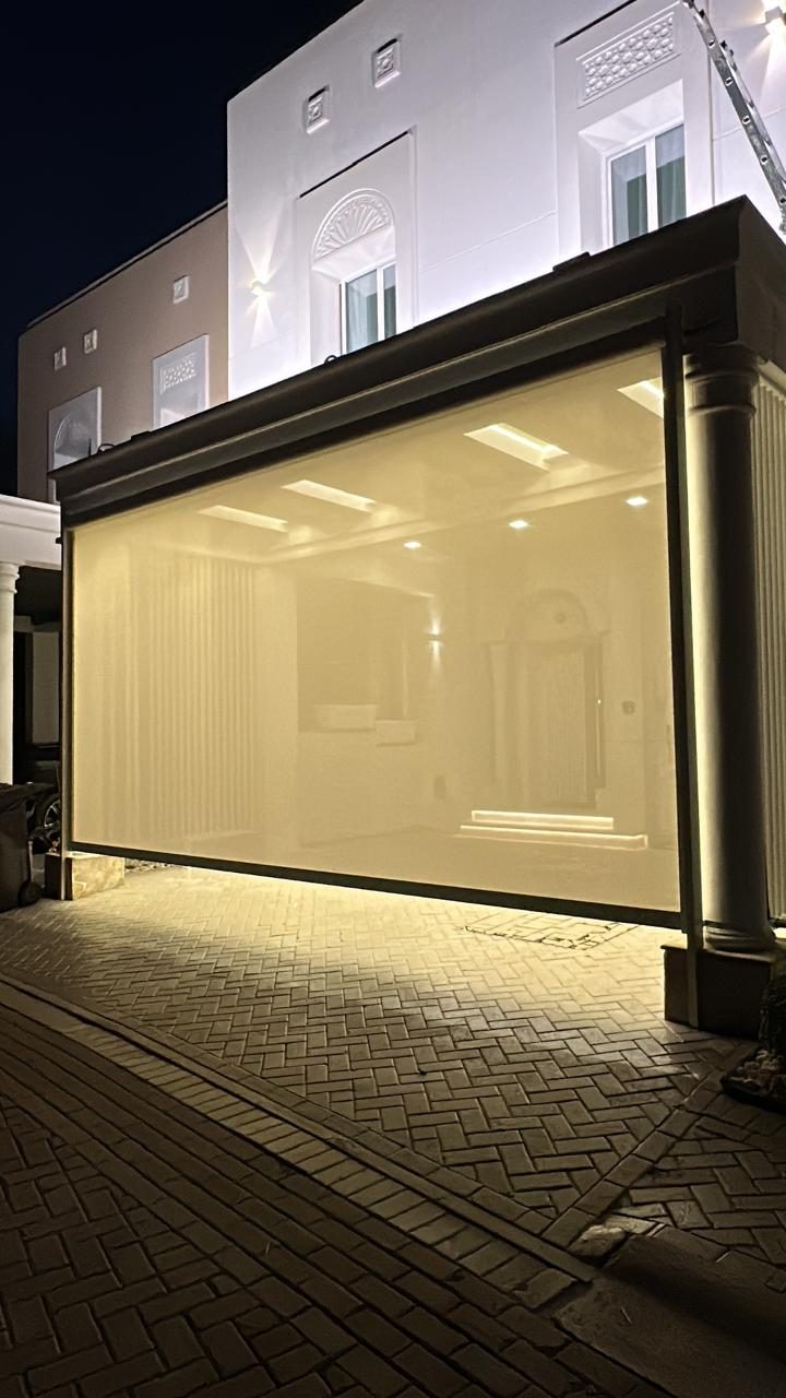 Villa extension at night with a full-height glass façade lit warmly from inside